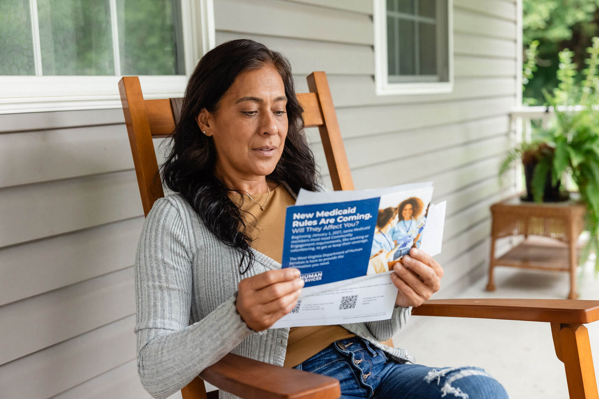 Woman reading a pamphlet on a rocking chair.