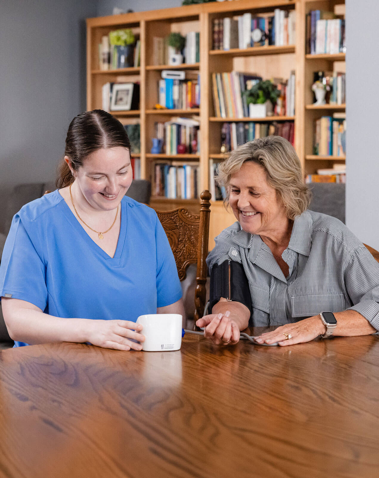 Nurse checking blood pressure at a dining room table.